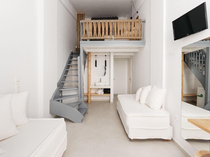 Jasny salon z białymi sofami, spiralnymi schodami i drewnianym antresolą w nowoczesnym pomieszczeniu.
