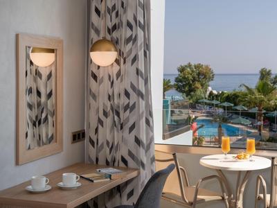 Nowoczesny balkon z stołem, krzesłami i widokiem na basen i morze w świetle dziennym.