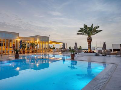 Nowoczesny basen o zachodzie słońca z podświetlaną wodą i palmami.