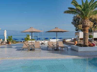 Luxuriöser Poolbereich mit Palmen und Blick auf das blaue Meer bei klarem Himmel.