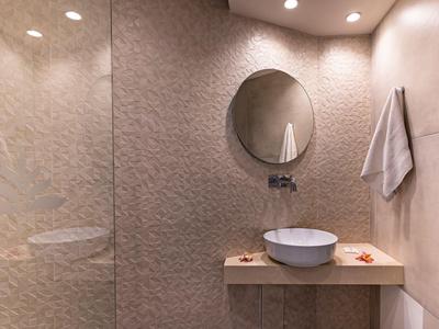 Nowoczesna, prosta łazienka z okrągłym lustrem, umywalką na drewnianej półce i ręcznikiem na ścianie.