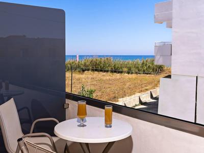 Balkon z dwoma szklankami soku pomarańczowego, widok na ogród i morze.