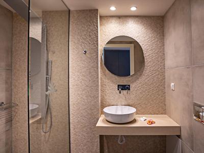 Nowoczesna łazienka z okrągłym lustrem i umywalką na prostym blacie.