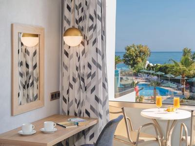 Balcón con mesa y sillas con vista al mar, pequeña mesa interior con tazas y espejo.