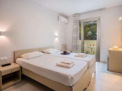 Jasny pokój dwuosobowy z balkonem, dwoma pojedynczymi łóżkami i nowoczesnym oświetleniem.