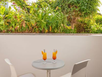 Dwa kolorowe koktajle na małym okrągłym stoliku z krzesłami na tarasie.