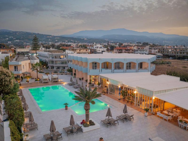 Nowoczesny kompleks hotelowy z basenem i otoczeniem w świetle wieczornym.