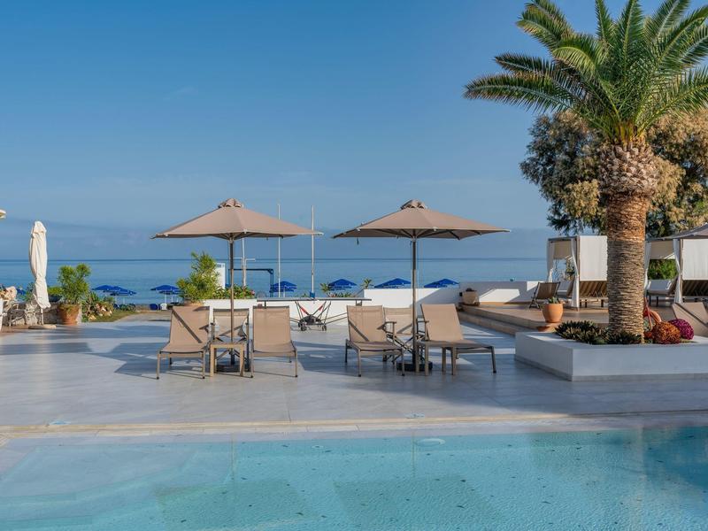 Luksusowy basen z palmami i widokiem na błękitne morze pod bezchmurnym niebem.