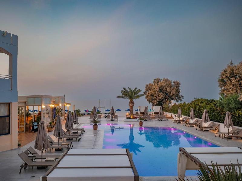 Przytulny basen hotelowy z leżakami i palmami o zachodzie słońca.