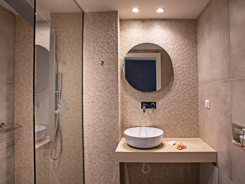 Nowoczesna łazienka z okrągłym lustrem i umywalką na prostym blacie.