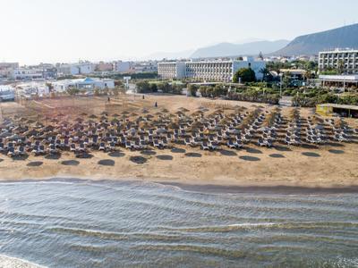 Pohled na rozsáhlou písčitou pláž s mnoha slunečníky a lehátky u hotelu.