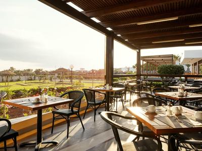 Terrazza coperta con tavoli e sedie con vista su un paesaggio verde al tramonto.