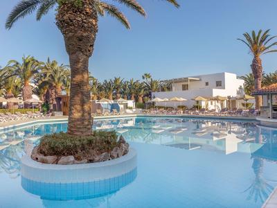 Piscina con palme e sdraio sotto un cielo sereno in un resort alberghiero.