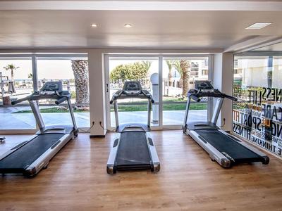 Tre tapis roulant in una palestra luminosa con grandi finestre che si affacciano su una piscina.