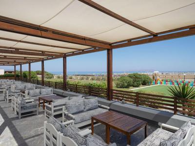 Terrazza all'aperto coperta con gruppi di posti a sedere e vista sul mare e sul giardino