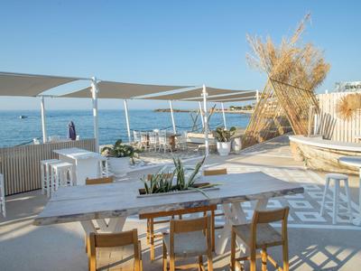 Ampia terrazza soleggiata con tavoli e vista sul mare sotto un cielo limpido.