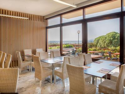 Ristorante moderno con grandi finestre che si affacciano su un'area esterna verde.