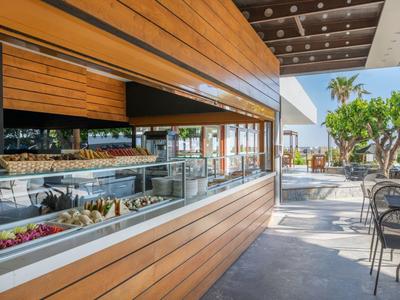 Moderní stánek s zmrzlinou s dřevěným obložením na slunné venkovní terase s židlemi a rostlinami.