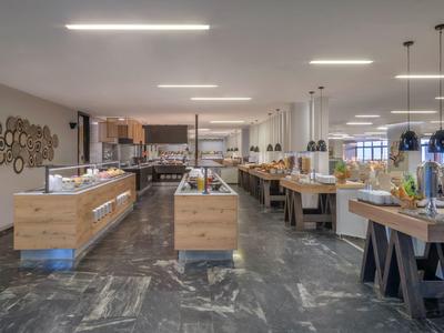 Moderní hotelový bufet s dřevěnými pulty, posezením a prostřenými stoly.