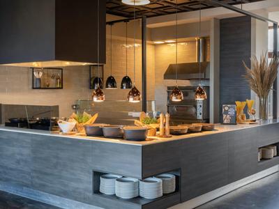 Moderní kuchyňský kout v hotelu s kuchyňským náčiním a dekorativním osvětlením.