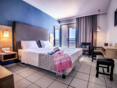 Moderní hotelový pokoj s manželskou postelí, jemným osvětlením, balkonem, psacím stolem a dlažbou