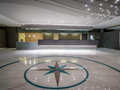 Moderní, elegantní hotelová recepce s osvětlenou přepážkou a mramorovou podlahou.