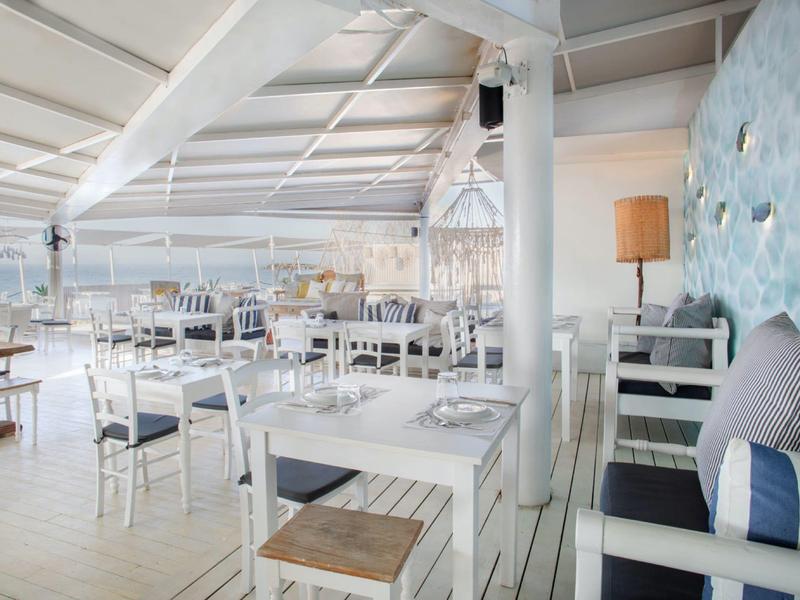 Světlá a přátelská restaurace s bílým zařízením a námořnickým dekorem.