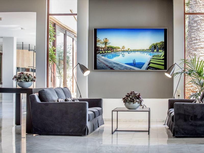 Moderní část hotelové haly s křesly a osvětlenou televizí na zdi