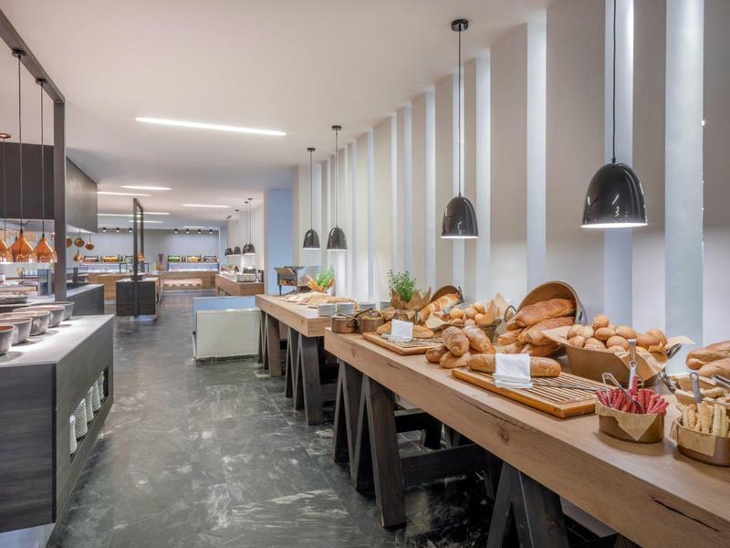 Moderní snídaňový bufet s čerstvým pečivem a světlým interiérem v elegantní hotelové jídelně.