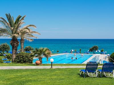 Due sdraio sull'erba accanto a una piscina con vista sul mare blu sotto un cielo limpido.