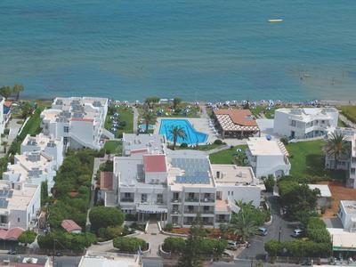 Veduta aerea di un complesso alberghiero bianco con piscina turchese di fronte al mare.