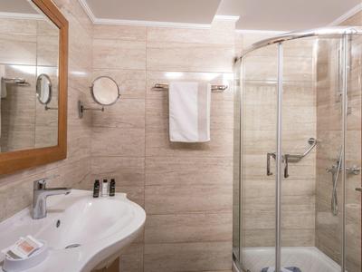 Bagno d'albergo con doccia, lavabo moderno e specchio con cornice in legno.