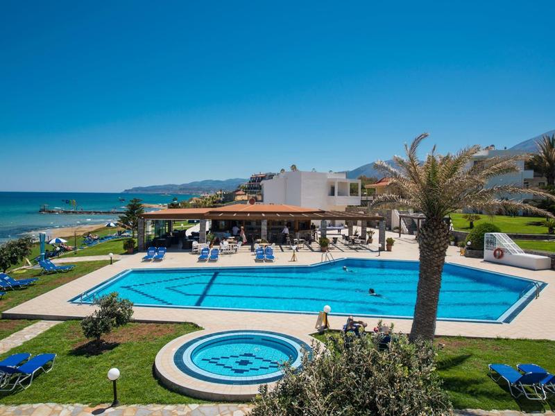 Piscina esterna con lettini e vista sul mare sotto un cielo sereno.