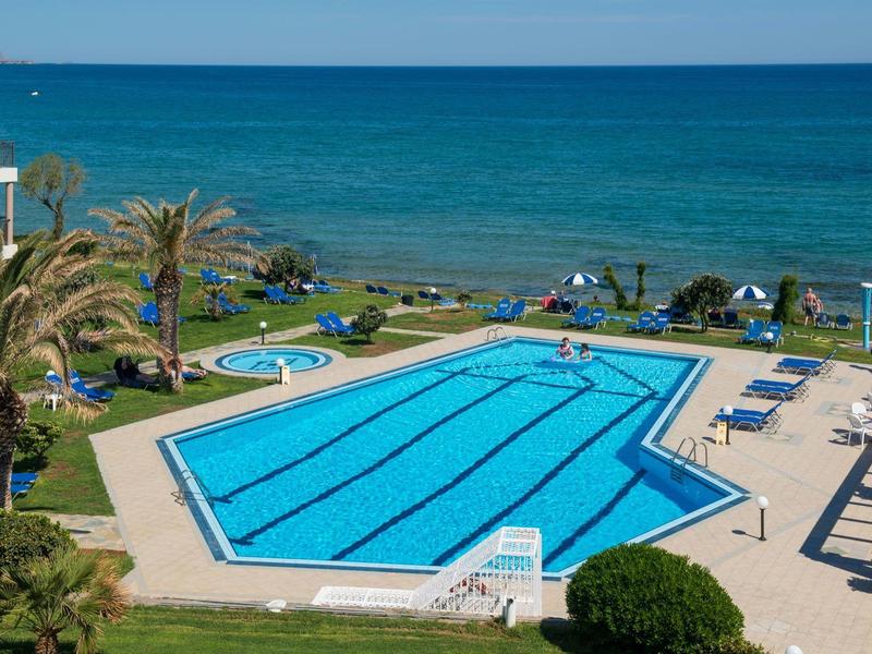 Piscina esagonale vicino al mare con lettini e palme verdi.