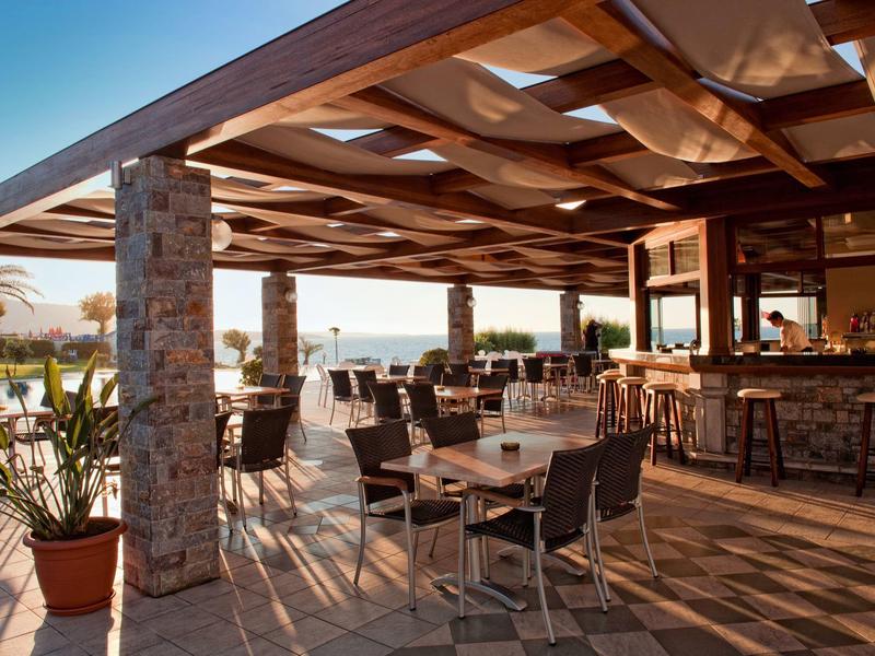 Terrazza esterna di un ristorante con tavoli, sedie e vista sul mare.