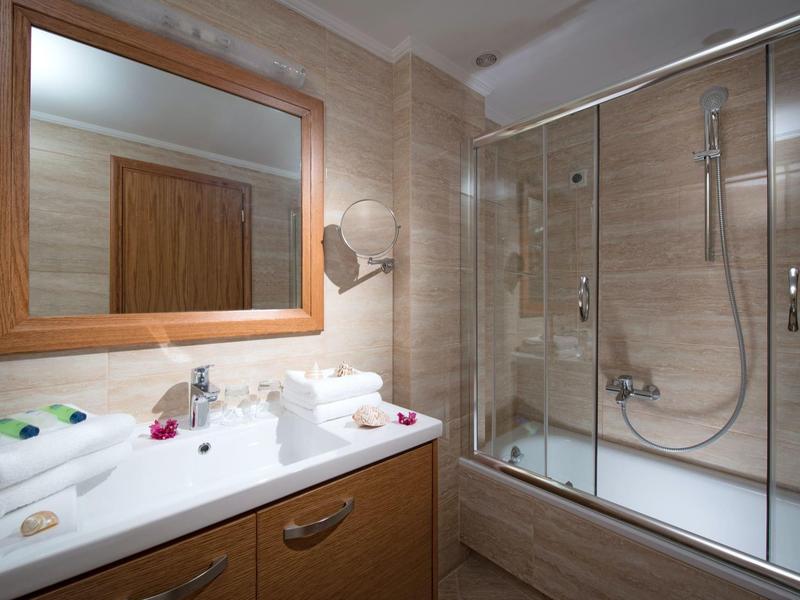 Bagno moderno con specchio incorniciato, lavabo, asciugamani e doccia con vetro.