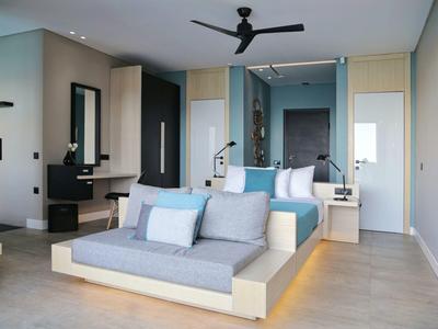 Nowoczesny pokój hotelowy z podwójnym łóżkiem, sofą, wentylatorem sufitowym i biurkiem.