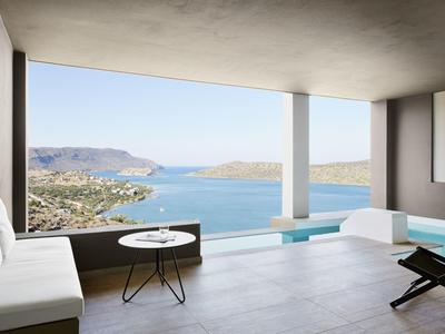 Terrazza moderna con divani bianchi che si affaccia su un mare blu e isole rocciose distanti.