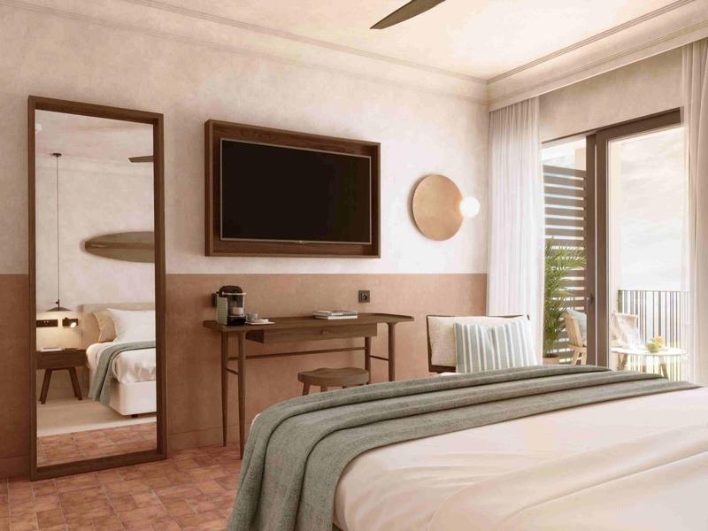 Przytulny pokój hotelowy z łóżkiem, biurkiem, lustrem, telewizorem i dużym oknem wpuszczającym naturalne światło.