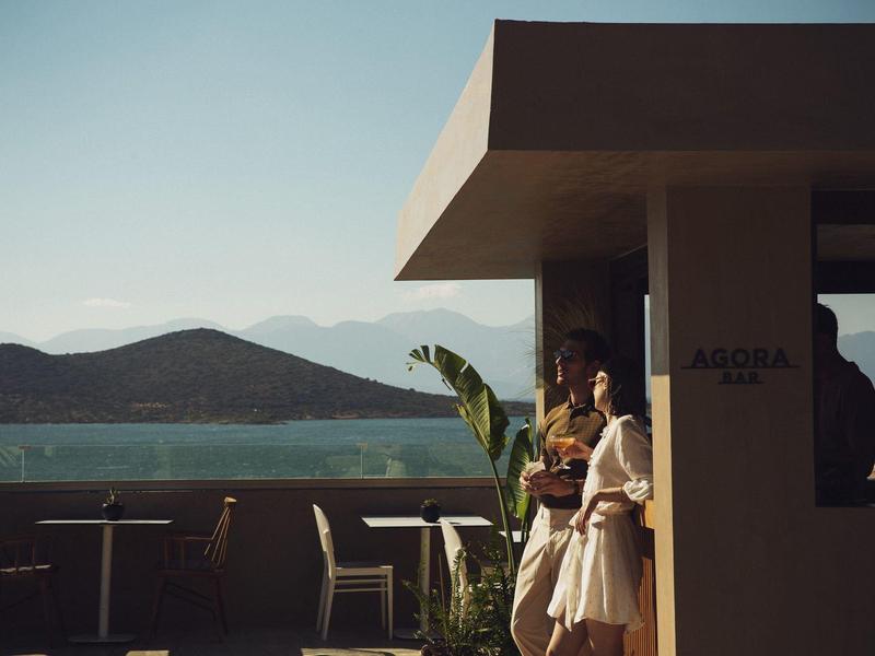 Para odpoczywająca na balkonie hotelu z widokiem na spokojne morze i odległe góry podczas zachodu słońca.