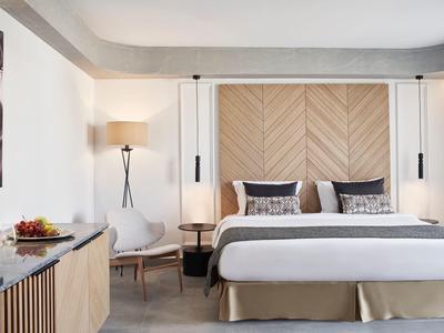 Moderne slaapkamer met groot bed, houten accenten en gezellige zitgelegenheid.