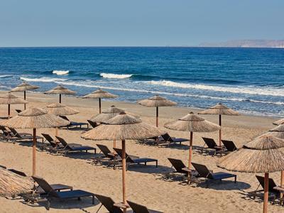 Leeg zandstrand met parasols en ligstoelen bij rustige zee.