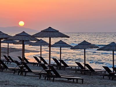 Zonsondergang boven de zee met zandstrand en lege ligstoelen onder parasols