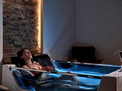 Vrouw ontspant in een modern spa-waterbekken met sfeerverlichting.