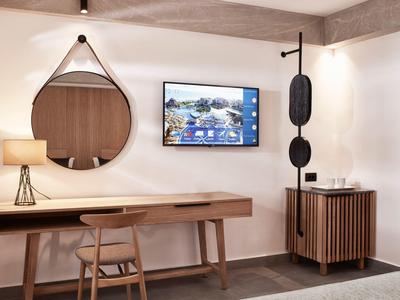 Moderne werkruimte in hotel met houten bureau, ronde spiegel en wand-tv.