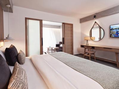 Modern ingerichte hotelkamer met groot bed en bureau met ronde spiegel.