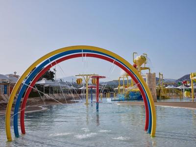 Kleurrijke waterspeelplaats met felle bogen en watersproeiers onder heldere hemel.