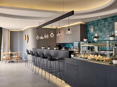 Moderne hotelbar met zwarte barkrukken en een balie met glazen verlichting.