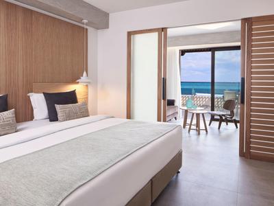 Modern hotelkamer met tweepersoonsbed en balkon met zeezicht.