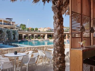 Moderne buitenzwembadgebied met waterval, zitplaatsen en palmbomen bij het hotel.